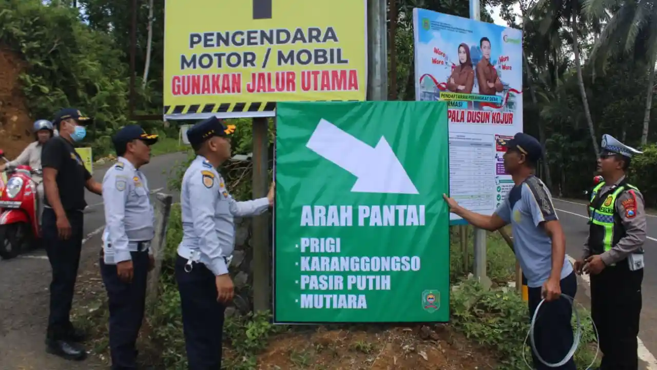 Petugas saat memasang rambu penunjuk arah jalur utama wisata Watulimo.